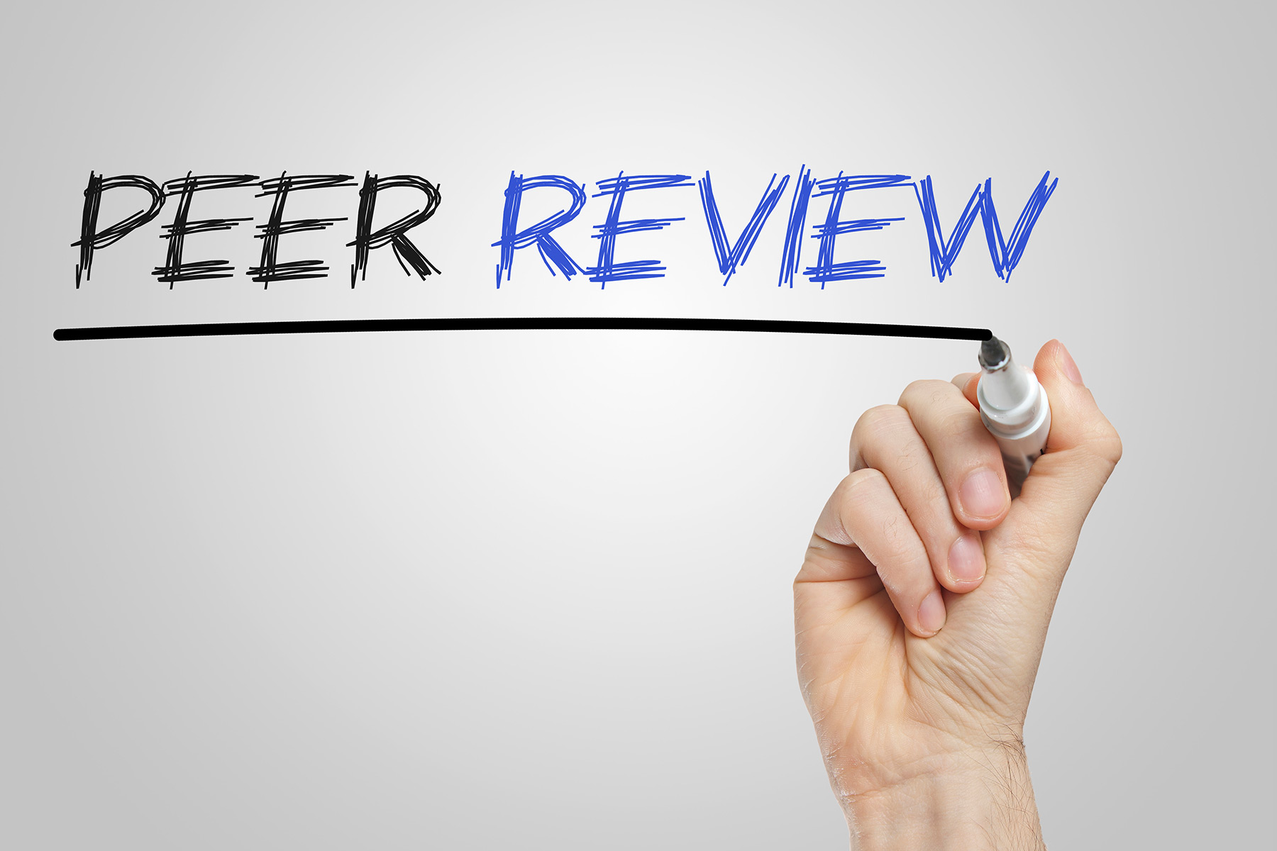 A hand holding a marker writes the words "PEER REVIEW" in large, sketch-style letters, underlined on a plain background.